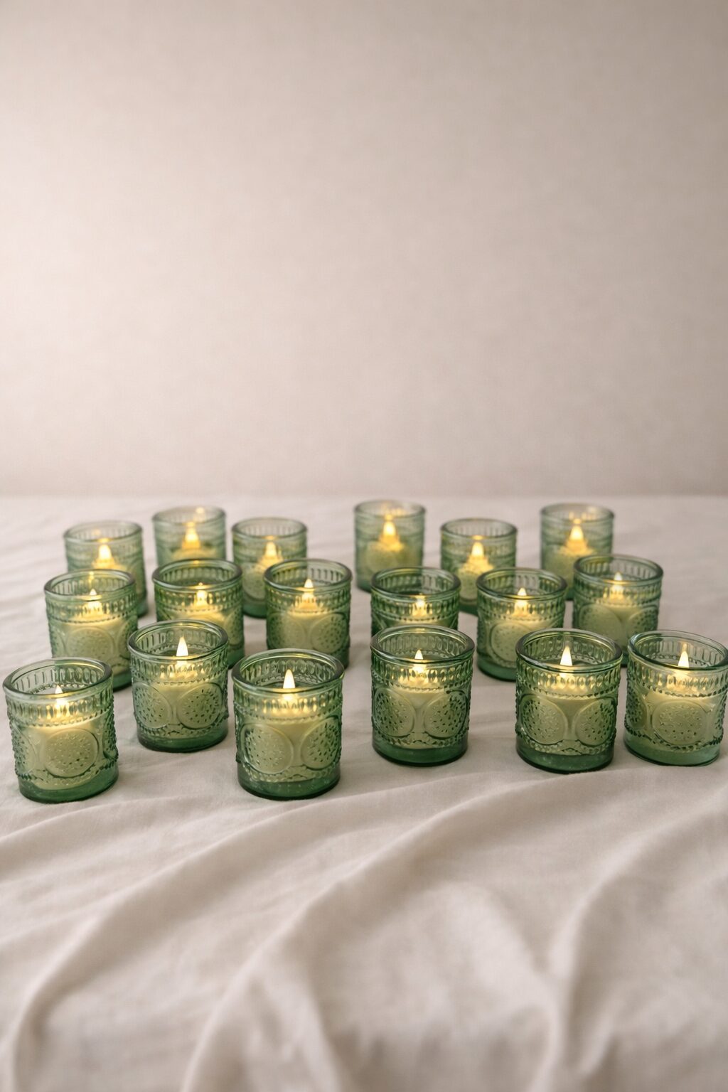 Castiçais votivos de vidro prensado verde com velas acesas